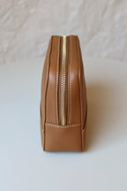 Soline Atelier EVERYDAY beauty case in camel leather with white stitching, gold logo and gold hardware, side view on a white background